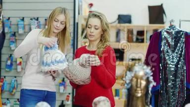两个年轻妇女在店里挑选一顶暖和的帽子。冬季购物